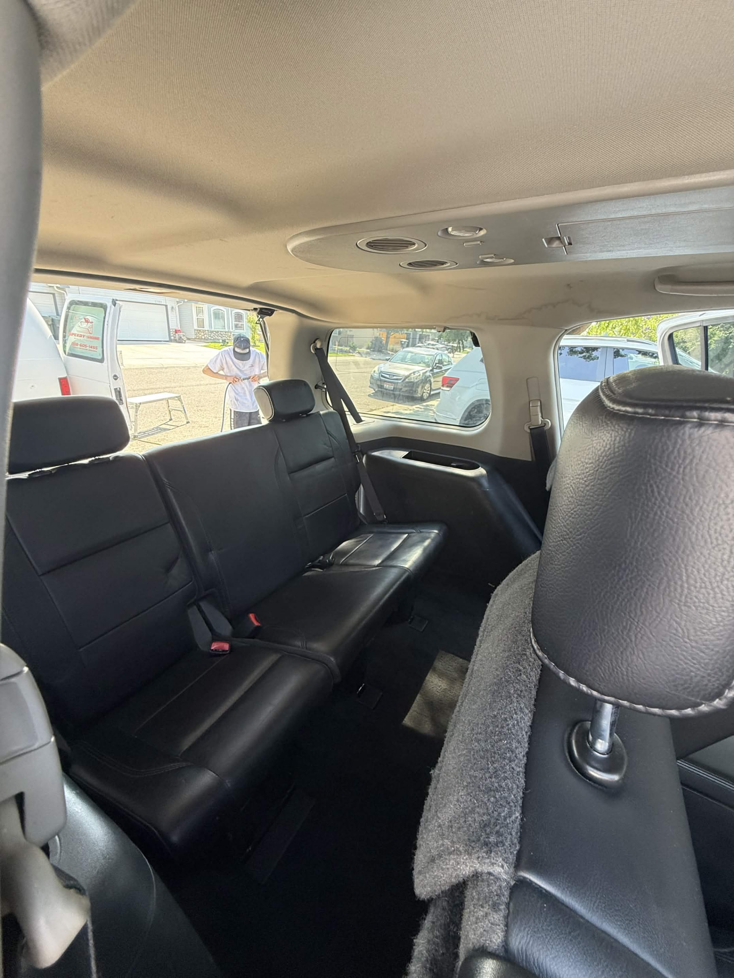 Clean black leather rear cabin of a large SUV with a Speedy Shine van outside