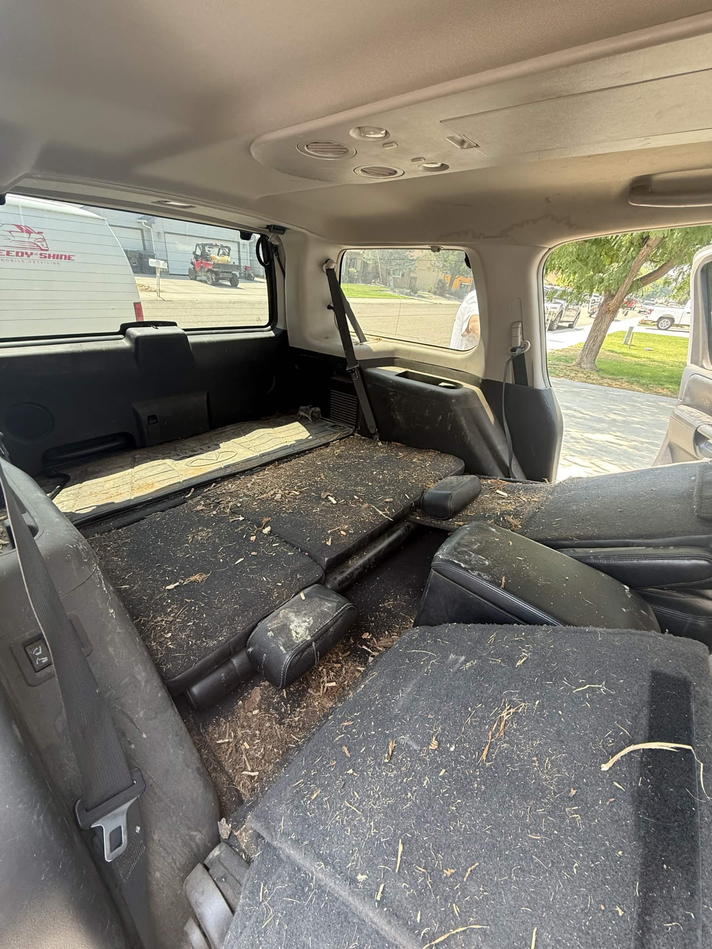 Cargo area of a large SUV with folded rear seats covered in dirt and leaves