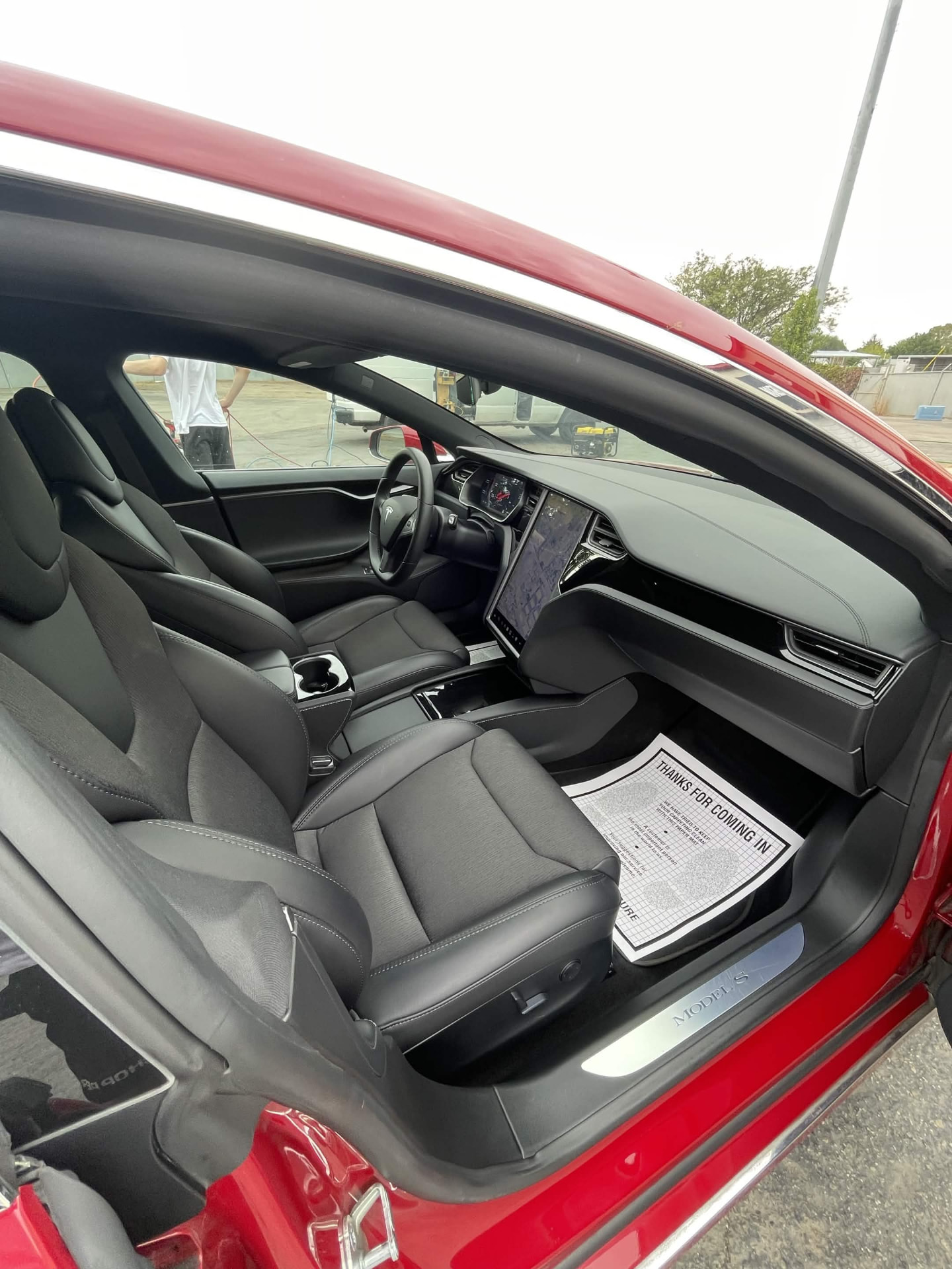 Black leather front cabin of a red Tesla Model S with clean seats, console and touchscreen