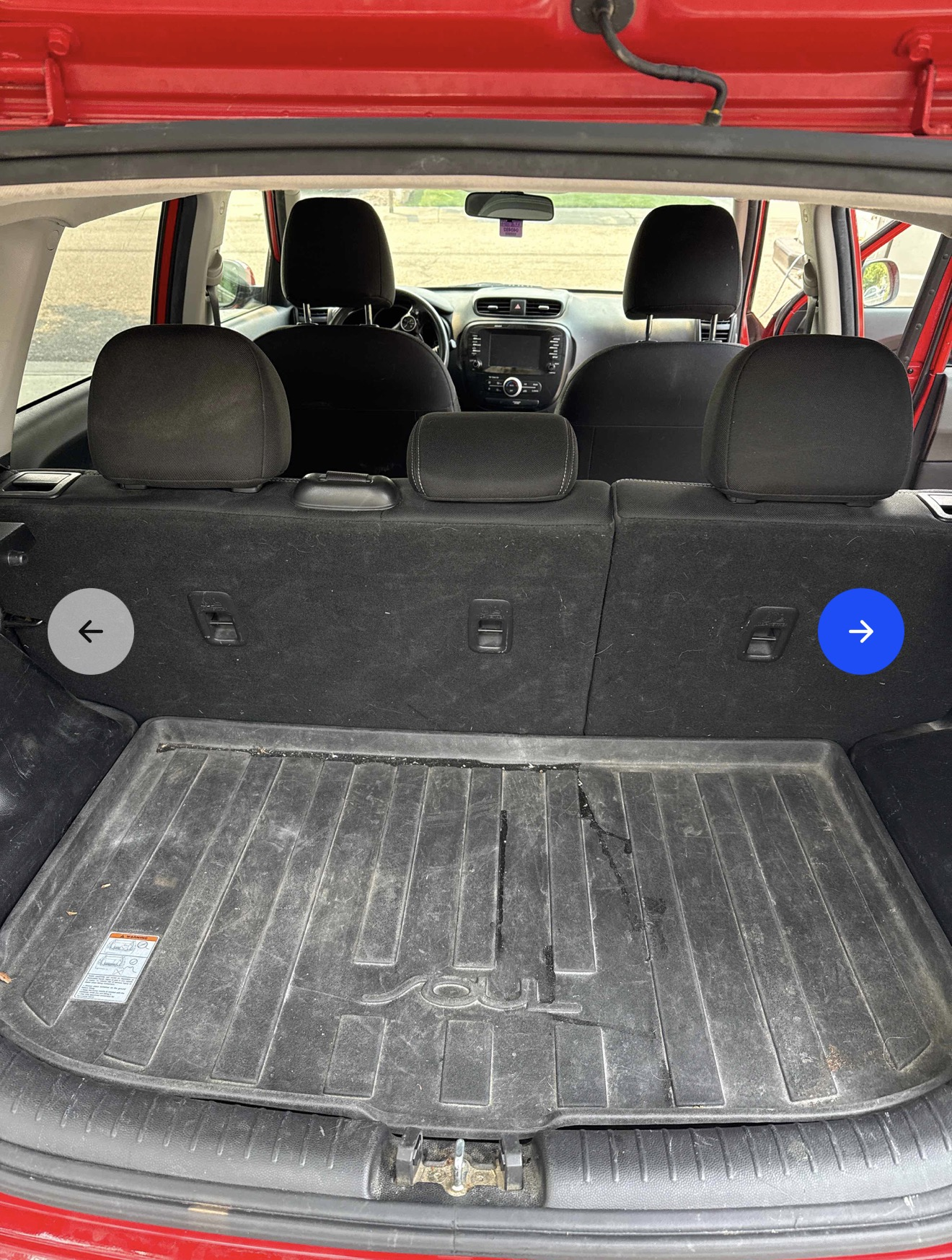 Dirty trunk of a red Kia Soul with stains and pet hair before detailing